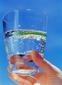Hand holding glass of sparkling water with lime slice --- Image by © Heide Benser/Corbis